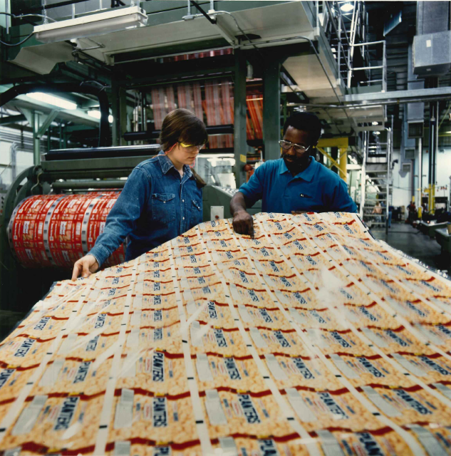 Dois funcionários manuseando algumas embalagens em um ambiente de fabricação.